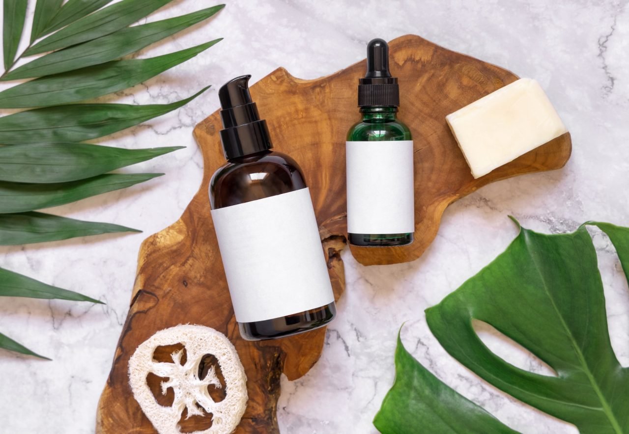 natural cosmetics in glass bottles on a wooden board near tropical leaves mockup top view.jpg