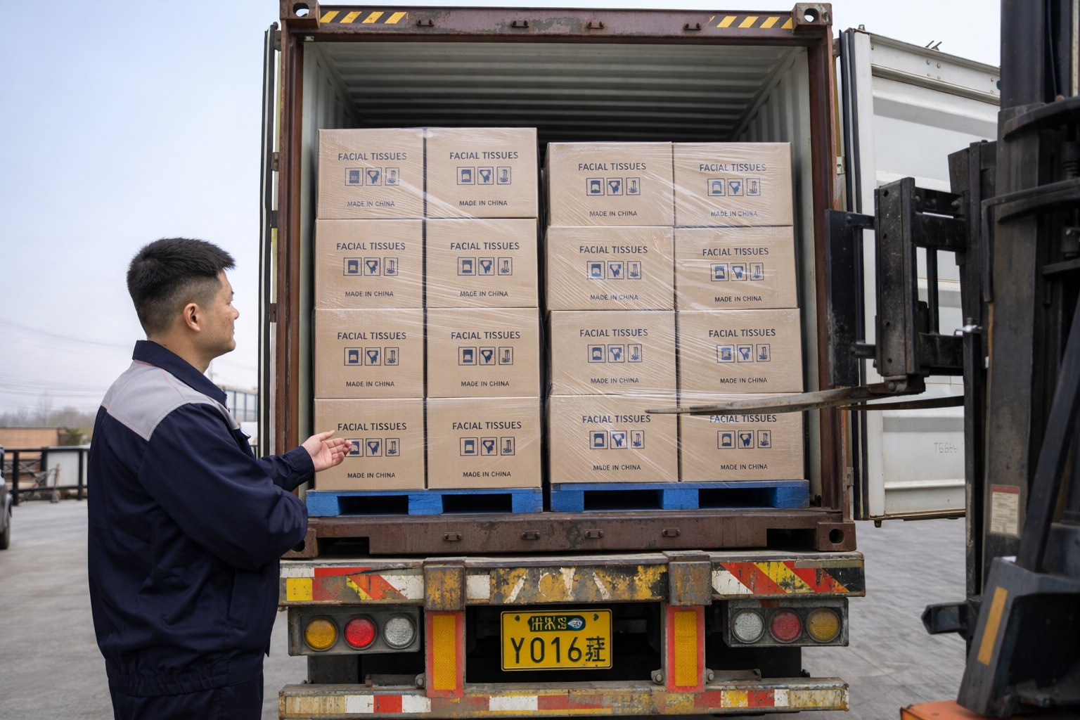 Facial tissue manufacturer worker inspecting palletized cartons loaded into export container
