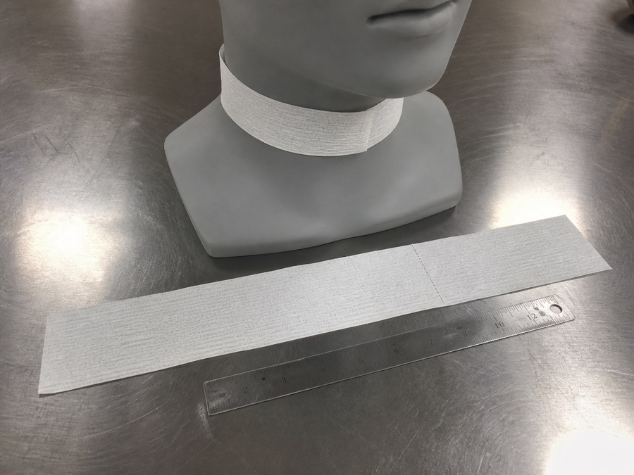 Disposable barber neck strip measured and fitted around a plain mannequin neck