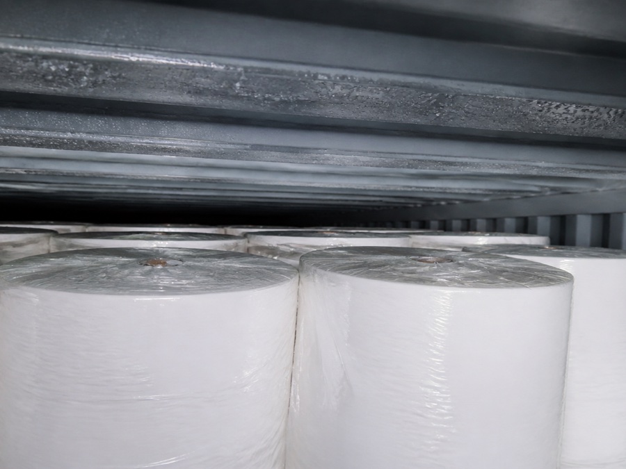 tissue mother roll supplier — close-up of small condensation droplets on a container roof above protected wrapped tissue rolls without product