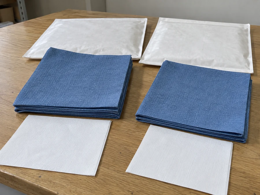 Paired blue napkin stacks, white sheets and sample envelopes