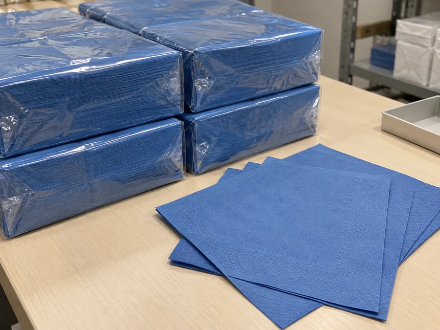 Wrapped blue napkin packs beside loose blue sheets