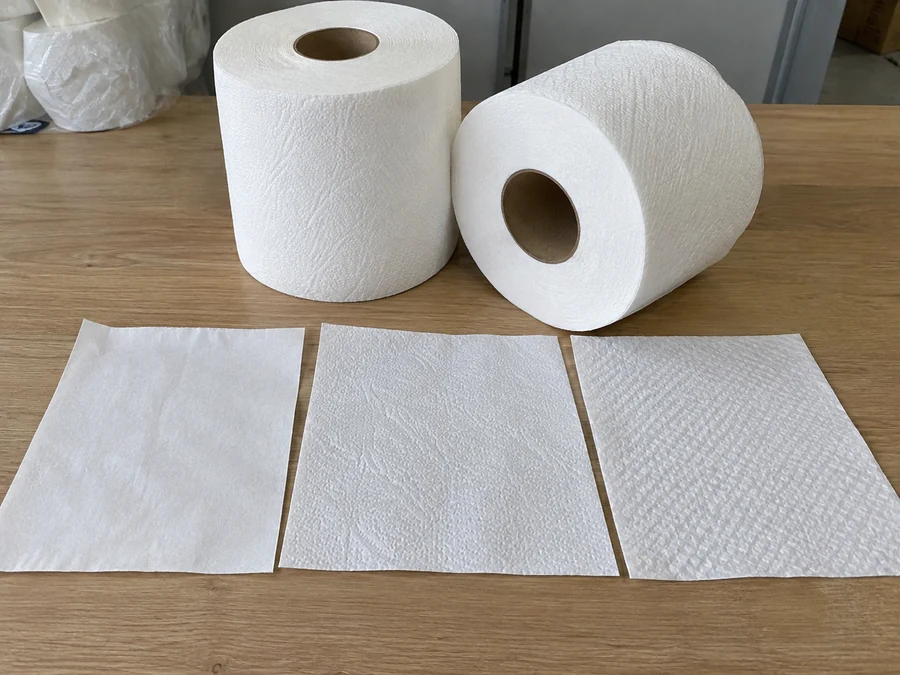 Two tissue rolls beside three textured sheet specimens