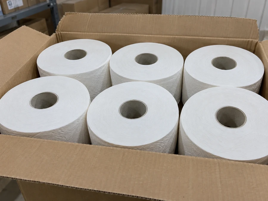 Six commercial toilet rolls arranged in an open shipping carton