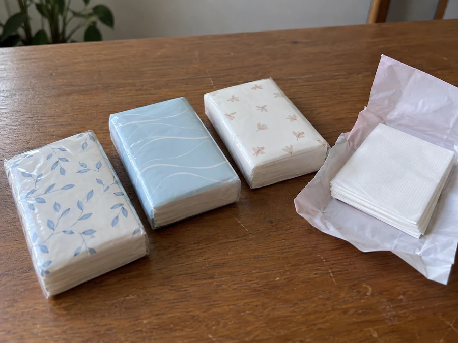 Slim wrapped tissue packets beside an opened pack of folded sheets