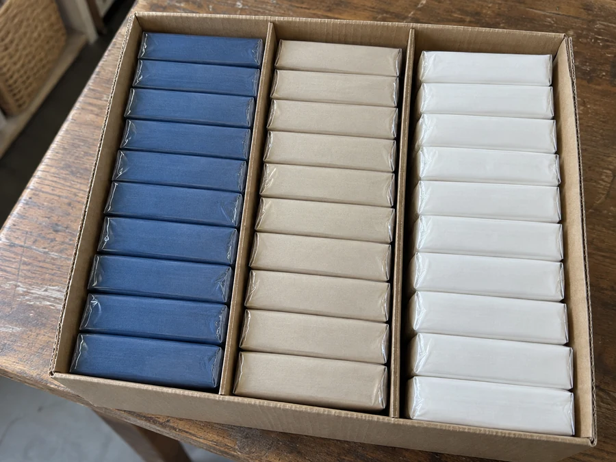 Three colors of pocket tissue packets separated inside a divided carton