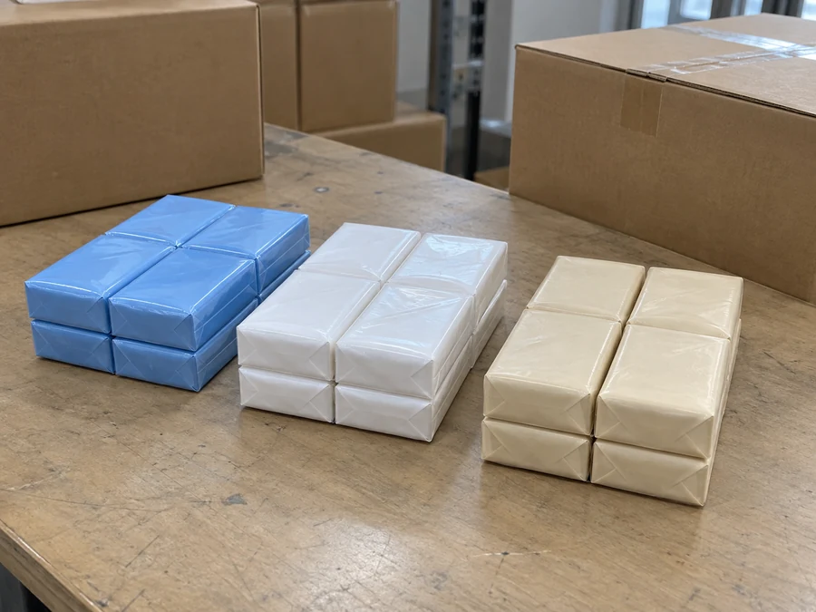 Sealed blue, white and beige tissue packets arranged beside cartons